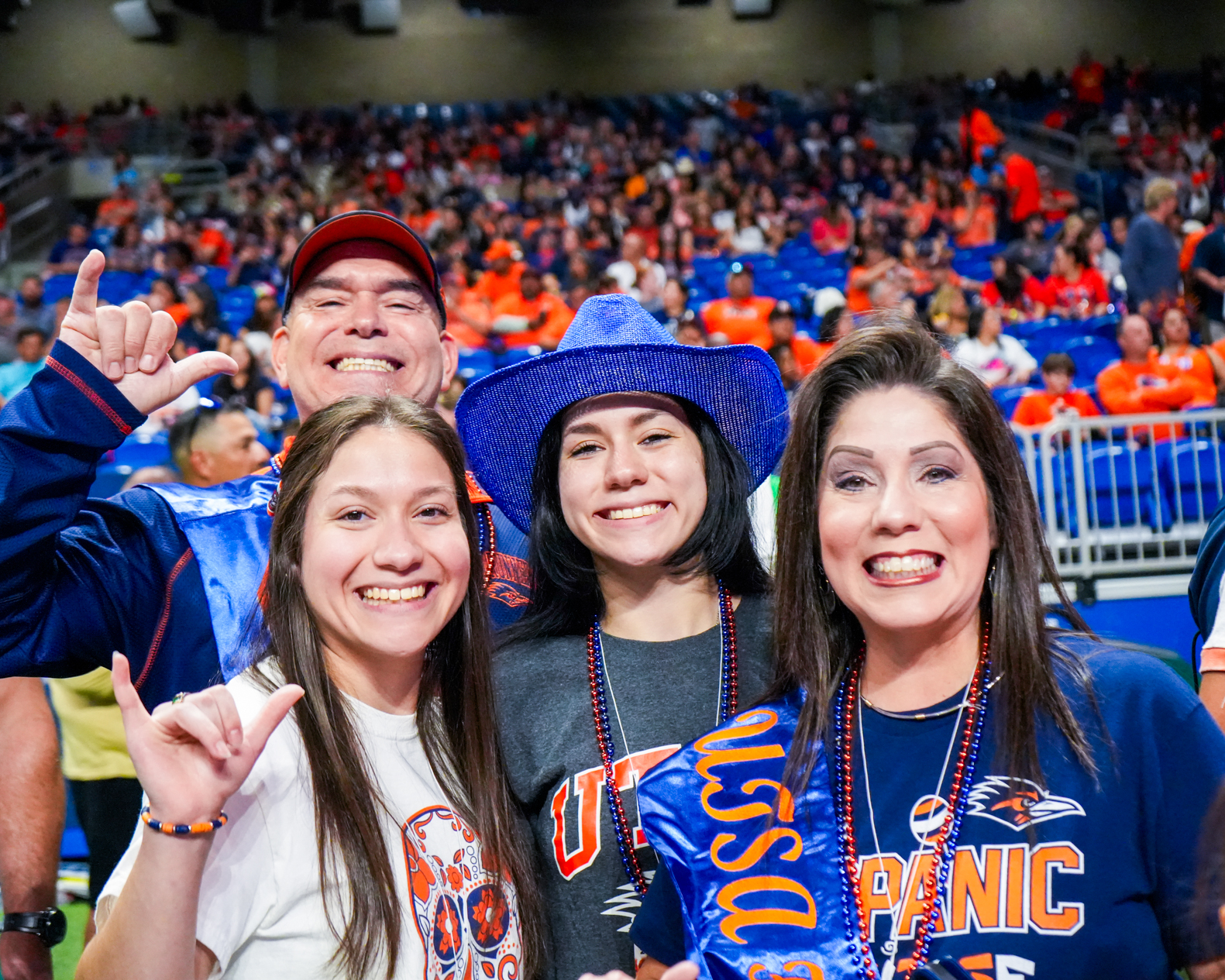 Family of four on football field making birds up UTSA hand sign